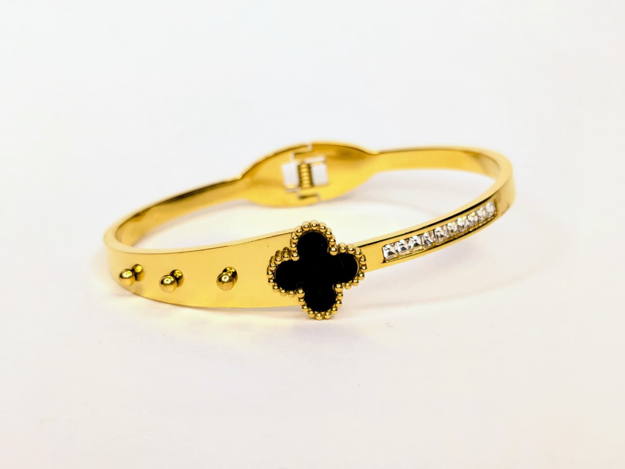 Gold bracelet with a black clover design on a white background